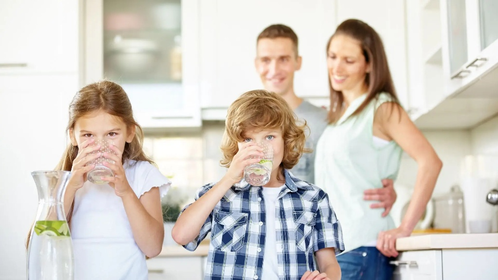 Famiglia felice in cucina mentre i bambini bevono acqua